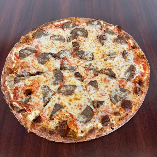 A whole Peoples Choice Pizza with sausage, melted cheese, and tomato sauce on a wooden table.