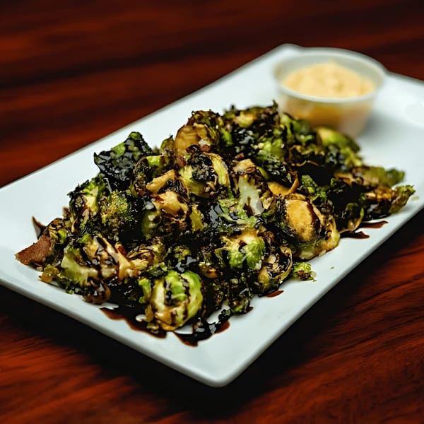 Roasted Brussels sprouts drizzled with balsamic glaze, served with a side of dipping sauce.